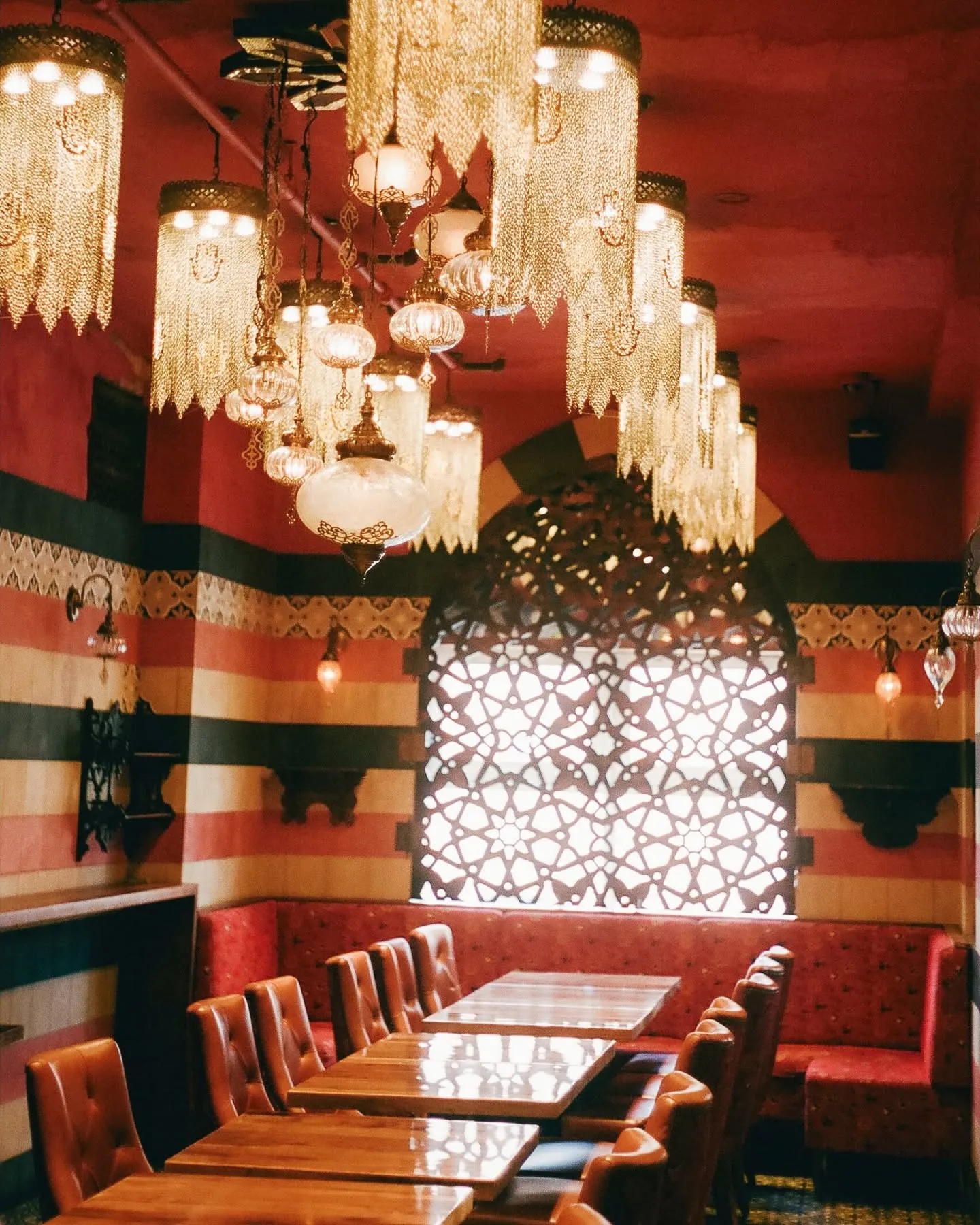 Salle aux murs rayés et moucharabieh lumineux sous les lustres